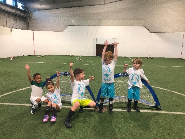 Children, each with one foot on their soccer ball, participating in a Kickin' Krakens class at Bremerton Sports Center